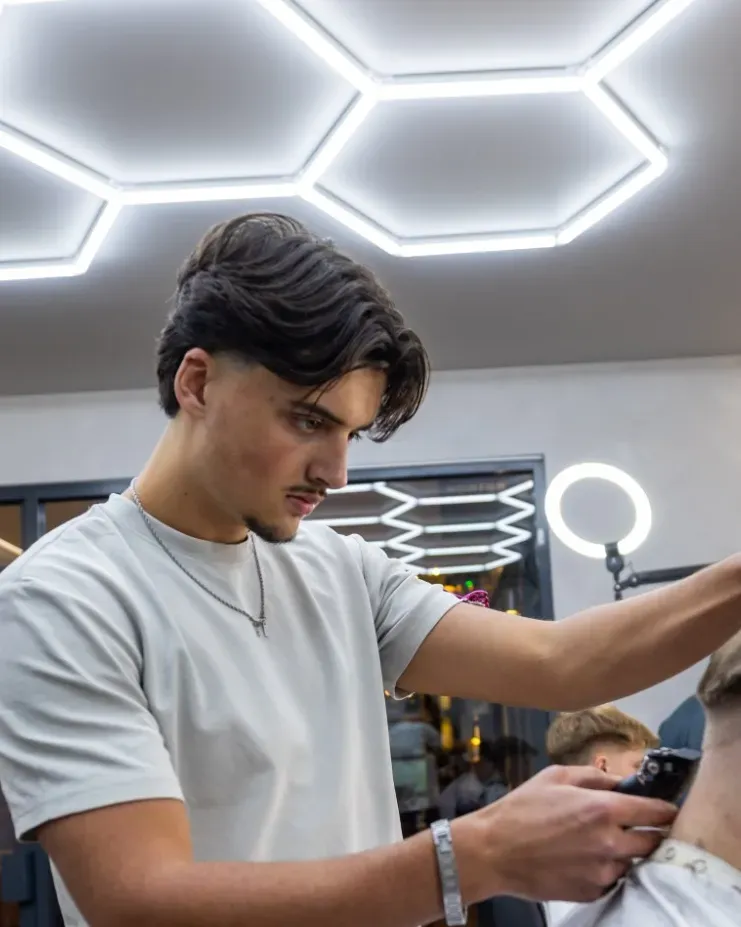 Evan fading a client's hair with clippers under the hex ceiling