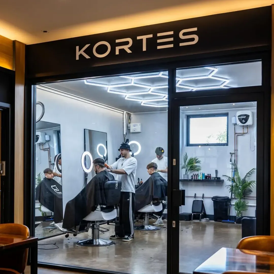 The studio front with barbers at work inside under the hex lights